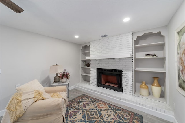 living room featuring a fireplace, hardwood / wood-style floors, and built in shelves