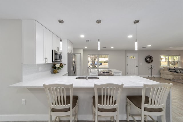 kitchen with a wealth of natural light, kitchen peninsula, sink, and appliances with stainless steel finishes