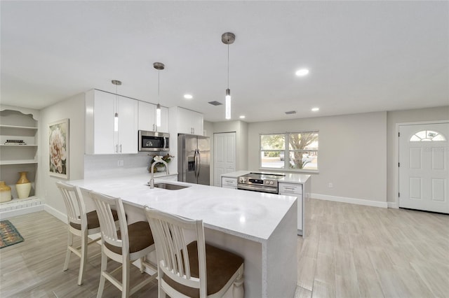 kitchen with sink, hanging light fixtures, kitchen peninsula, white cabinets, and appliances with stainless steel finishes