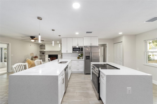 kitchen with white cabinets, sink, hanging light fixtures, appliances with stainless steel finishes, and kitchen peninsula