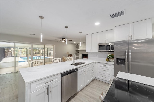 kitchen with sink, white cabinets, hanging light fixtures, and appliances with stainless steel finishes