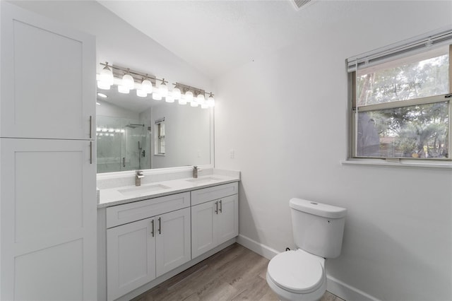 bathroom with vanity, hardwood / wood-style floors, lofted ceiling, toilet, and a shower with shower door