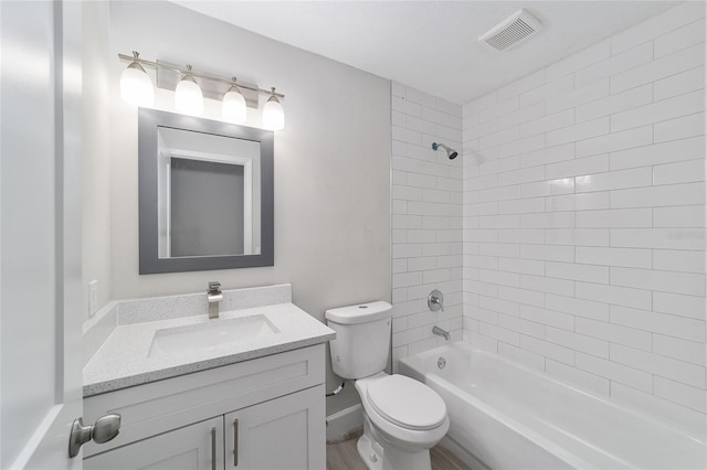 full bathroom with vanity, tiled shower / bath, and toilet