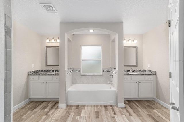 bathroom featuring a bath, vanity, wood-type flooring, and a textured ceiling