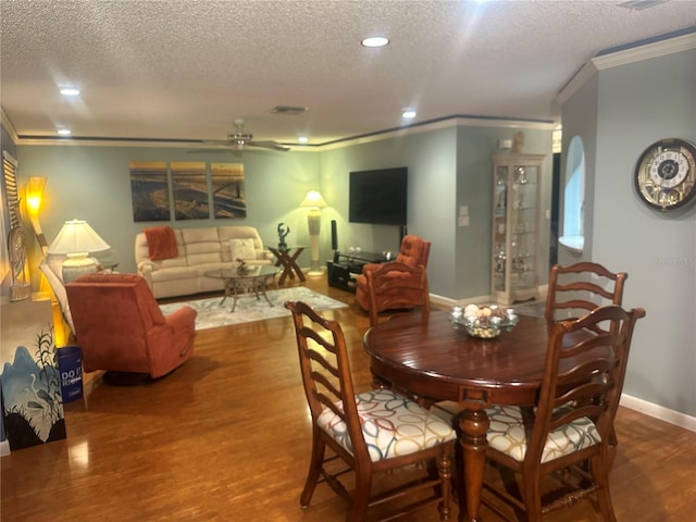 dining space featuring hardwood / wood-style floors, ceiling fan, ornamental molding, and a textured ceiling