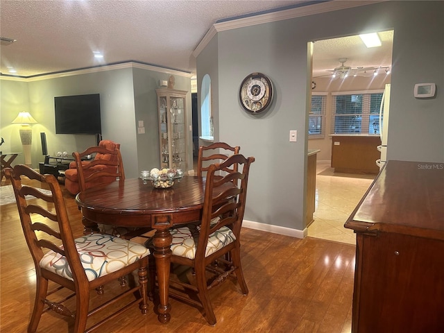 dining room featuring crown molding, a textured ceiling, and light wood-type flooring