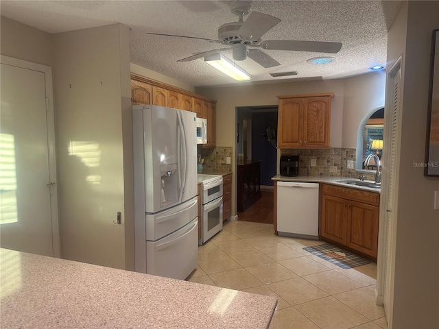 kitchen featuring a textured ceiling, sink, light tile patterned floors, and white appliances