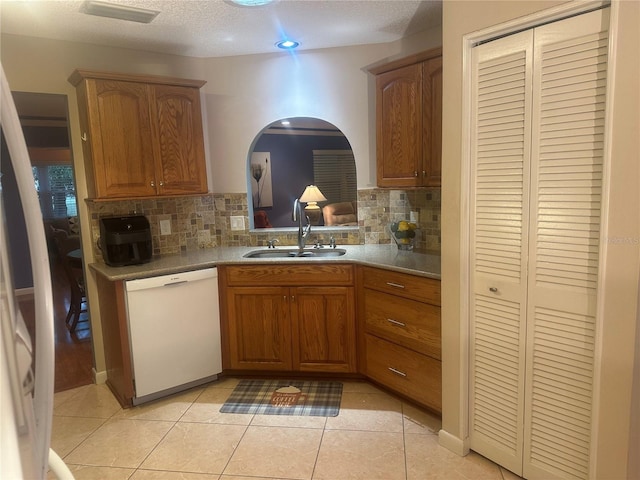 kitchen featuring decorative backsplash, a textured ceiling, sink, dishwasher, and light tile patterned flooring