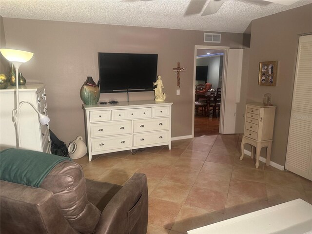 living room with ceiling fan, light tile patterned flooring, and a textured ceiling