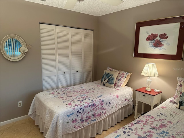 bedroom with a textured ceiling, a closet, ceiling fan, and light tile patterned flooring