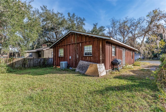 view of side of property with a lawn and central AC