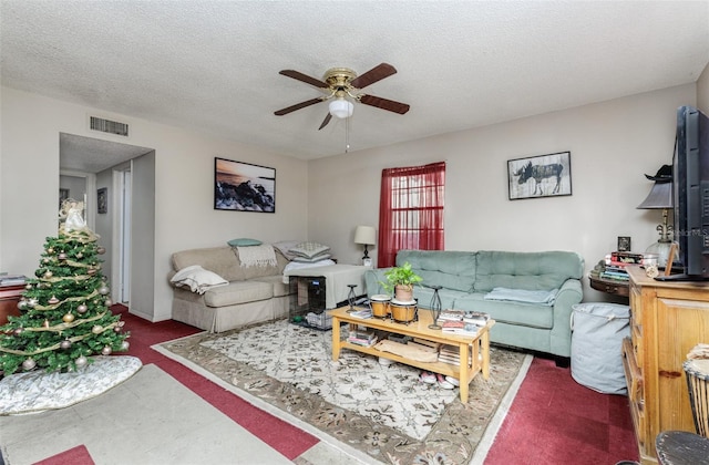 carpeted living room with ceiling fan and a textured ceiling