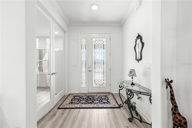 foyer with a textured ceiling, crown molding, light hardwood / wood-style flooring, and plenty of natural light