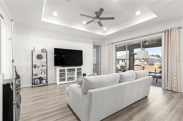 living room with crown molding, light hardwood / wood-style flooring, and a tray ceiling