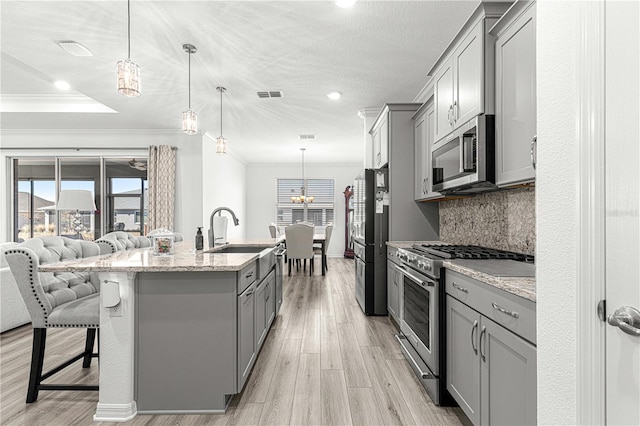 kitchen featuring decorative backsplash, appliances with stainless steel finishes, light wood-type flooring, gray cabinetry, and pendant lighting