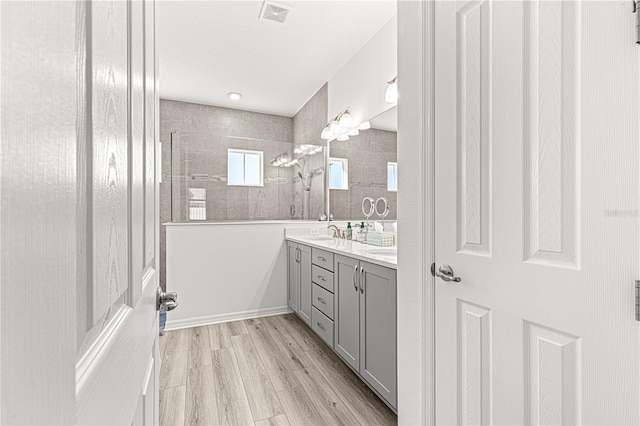 bathroom featuring hardwood / wood-style floors, vanity, and a tile shower