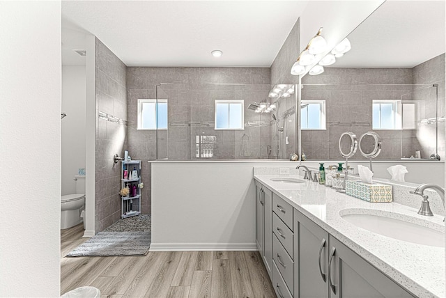 bathroom featuring hardwood / wood-style flooring, vanity, a healthy amount of sunlight, and tiled shower