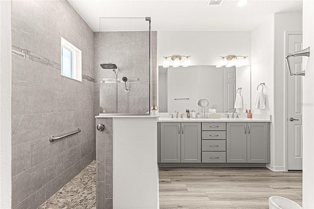 bathroom with hardwood / wood-style floors, vanity, and tiled shower