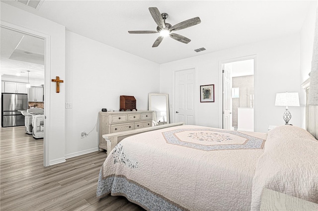 bedroom with hardwood / wood-style floors, ensuite bathroom, ceiling fan, and stainless steel refrigerator