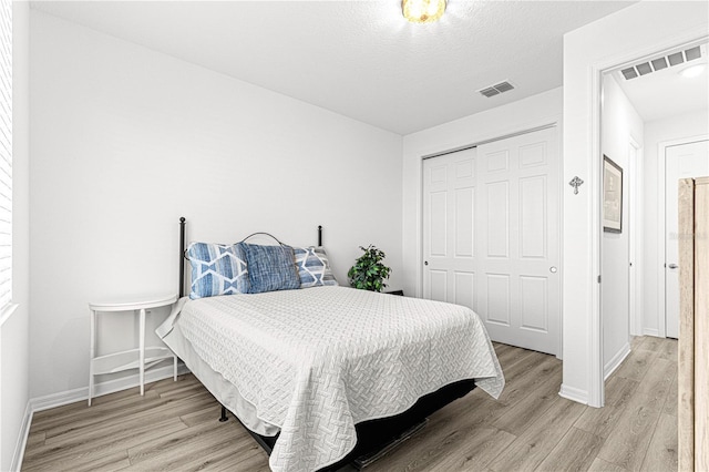 bedroom with a closet, light hardwood / wood-style floors, and a textured ceiling