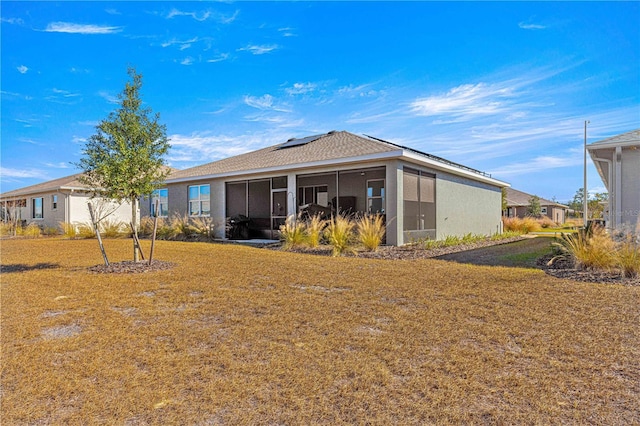 back of house featuring a lawn and a sunroom