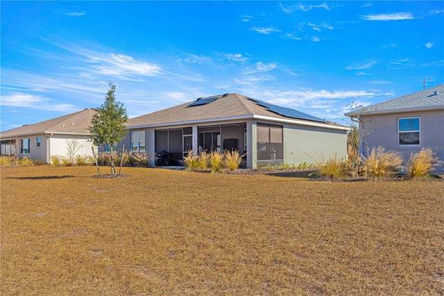 back of property with solar panels, a lawn, and a sunroom