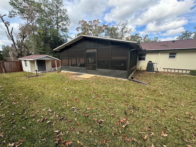 rear view of property with a yard, central AC unit, and a storage unit