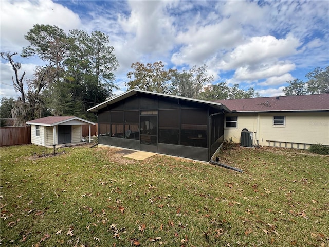 back of property with a lawn, a shed, a sunroom, and central AC unit