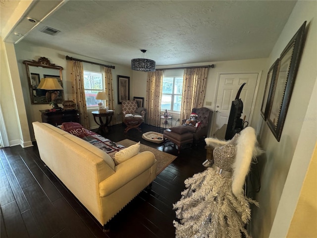 living room featuring a textured ceiling, dark wood-type flooring, and a wealth of natural light