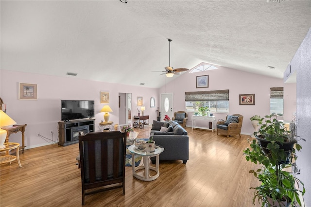 living room featuring a textured ceiling, light hardwood / wood-style floors, vaulted ceiling, and ceiling fan