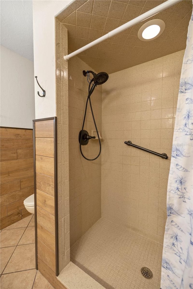 bathroom featuring toilet, tile patterned floors, walk in shower, and wooden walls