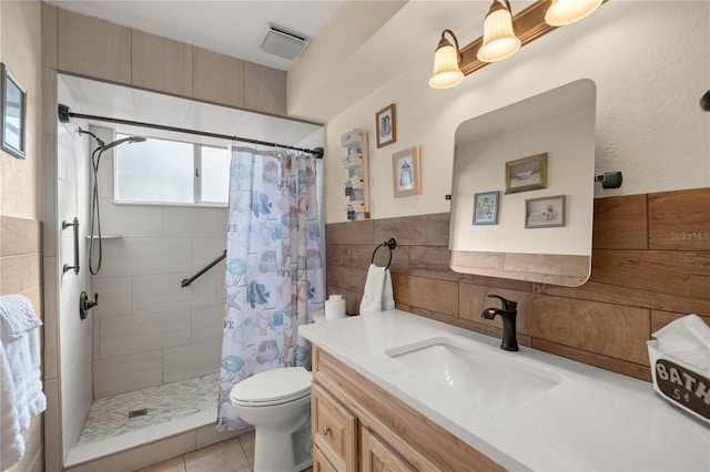 bathroom with curtained shower, tile patterned flooring, toilet, vanity, and tile walls