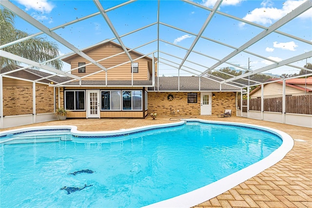 view of swimming pool featuring glass enclosure and a patio