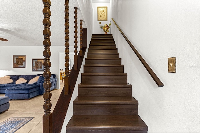 stairway with tile patterned flooring and a textured ceiling