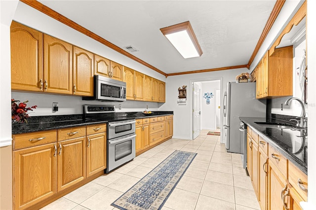 kitchen featuring sink, crown molding, dark stone countertops, appliances with stainless steel finishes, and light tile patterned flooring