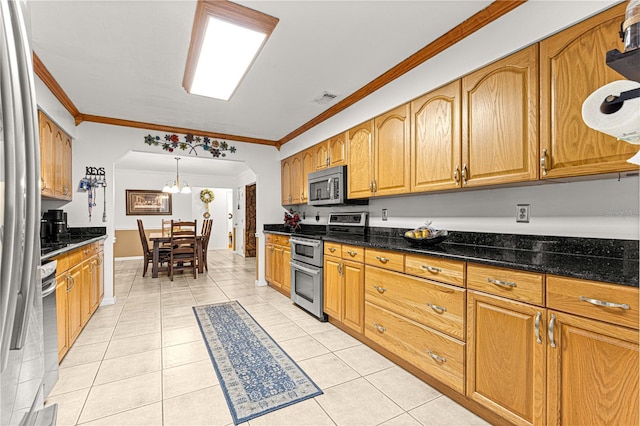 kitchen featuring light tile patterned floors, ornamental molding, decorative light fixtures, and appliances with stainless steel finishes