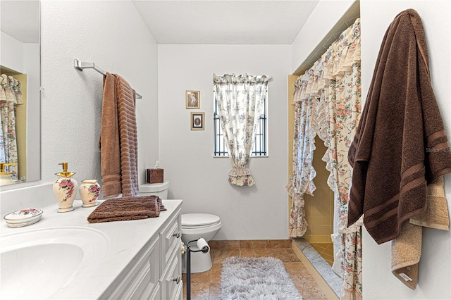 bathroom featuring tile patterned floors, vanity, toilet, and walk in shower