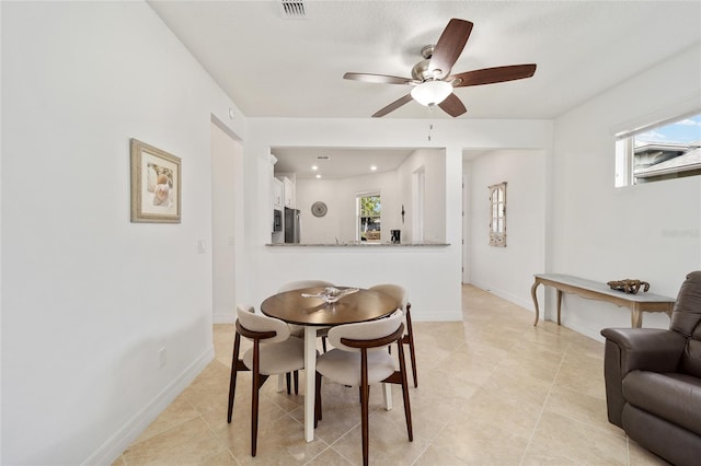 tiled dining space featuring plenty of natural light and ceiling fan