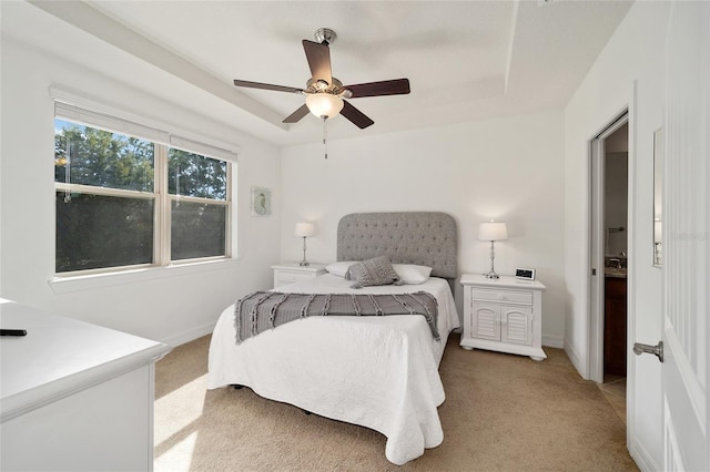 bedroom featuring ceiling fan, light carpet, and a tray ceiling