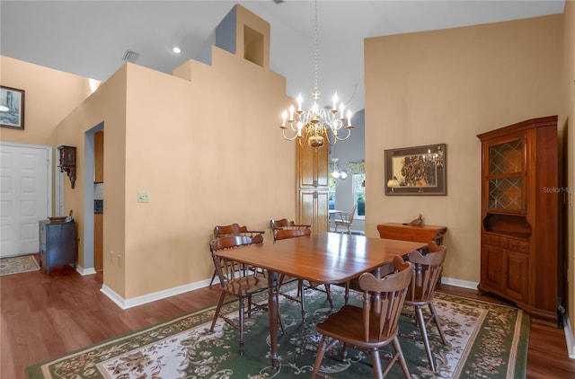 dining space with hardwood / wood-style flooring, a towering ceiling, and a chandelier