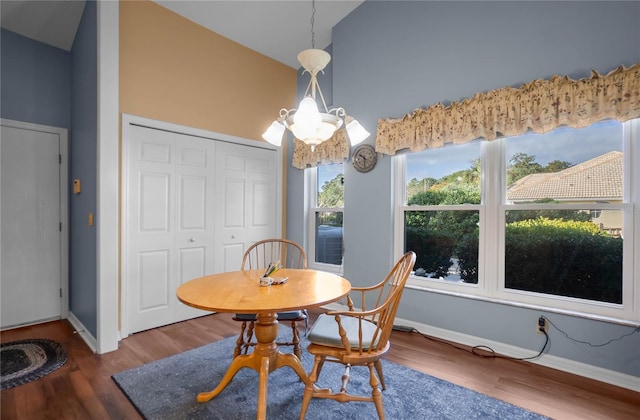 dining area with hardwood / wood-style flooring, a notable chandelier, and high vaulted ceiling