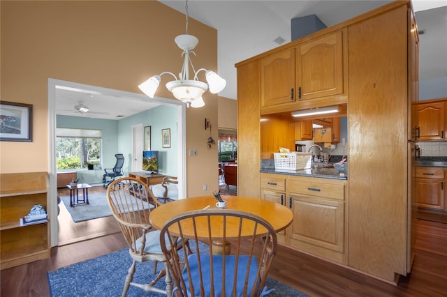 dining room with high vaulted ceiling, dark wood-type flooring, and ceiling fan with notable chandelier