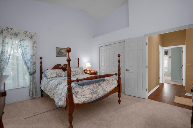 bedroom with hardwood / wood-style floors, a closet, high vaulted ceiling, and multiple windows