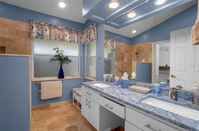 bathroom with vanity, lofted ceiling, and tiled shower