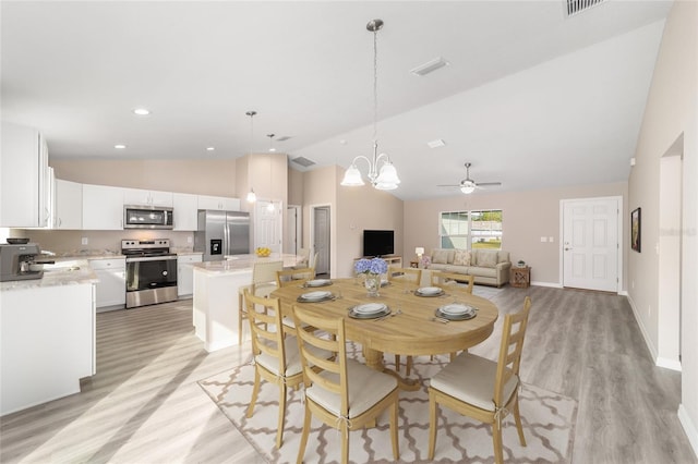 dining area featuring sink, ceiling fan with notable chandelier, lofted ceiling, and light wood-type flooring