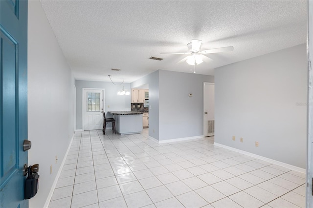 unfurnished living room featuring ceiling fan with notable chandelier, light tile patterned floors, and a textured ceiling