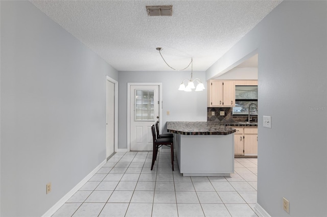 kitchen with hanging light fixtures, a notable chandelier, kitchen peninsula, decorative backsplash, and a breakfast bar