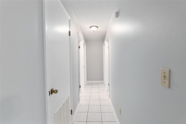 hallway featuring light tile patterned floors and a textured ceiling