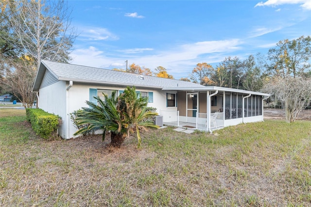 rear view of house featuring a sunroom, a yard, and central AC