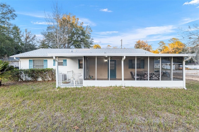 back of property with a lawn and a sunroom